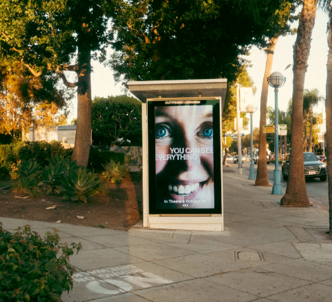 Street furniture de A24 en Nueva York con un primer plano extremo de un rostro y el mensaje You Can See Everything.