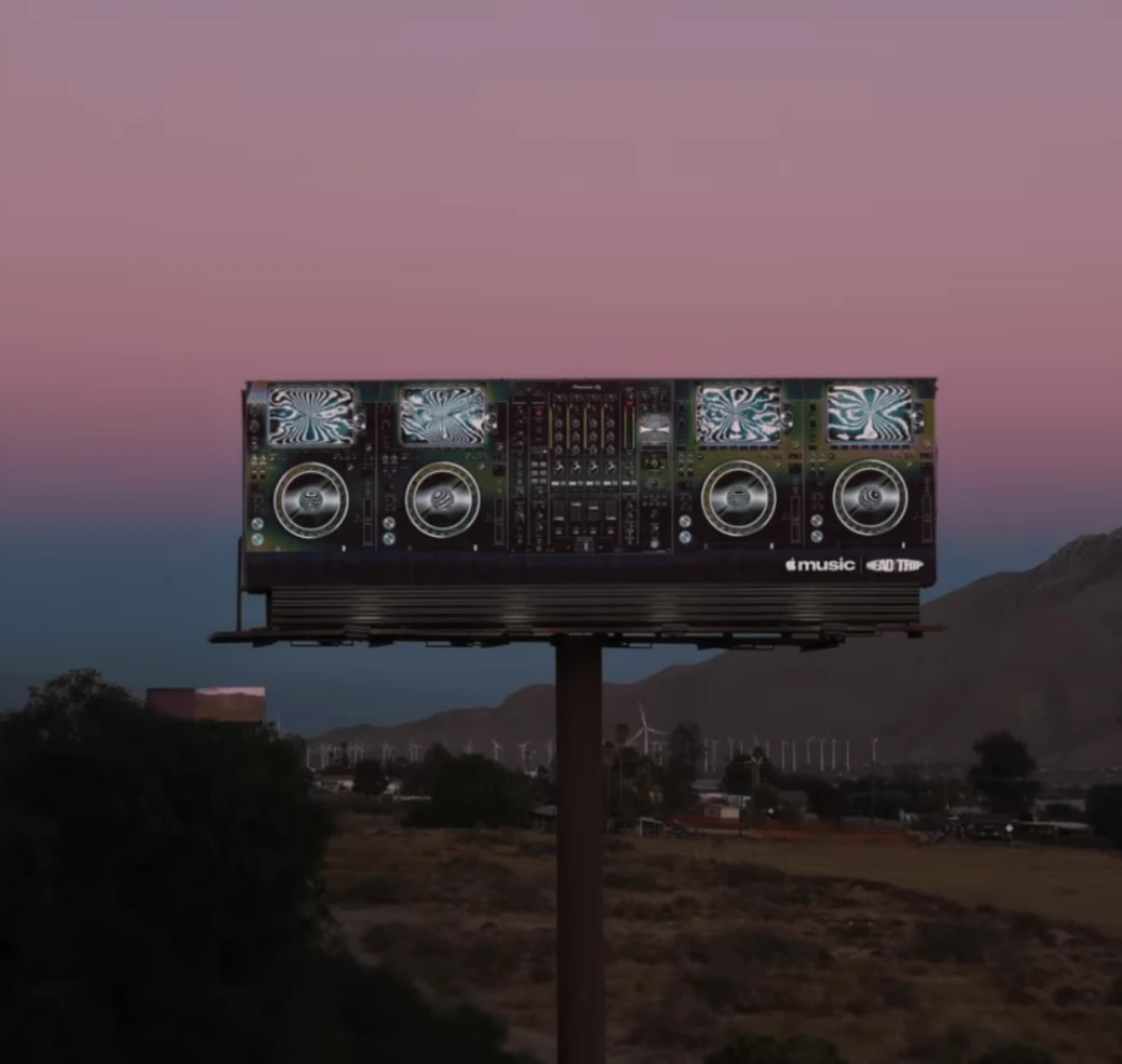 Espectacular de Apple Music para Head Trip Indio diseñado como una consola de DJ sobre carretera al atardecer.