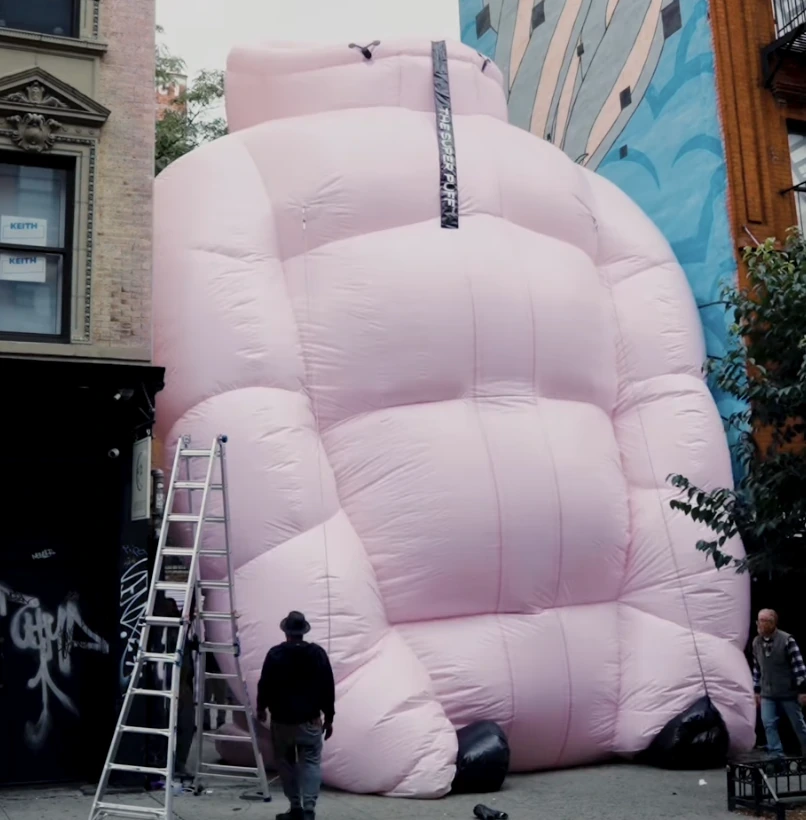 Proceso de instalación del Super Puff gigante de Aritzia en Nueva York con una escalera y personas alrededor.