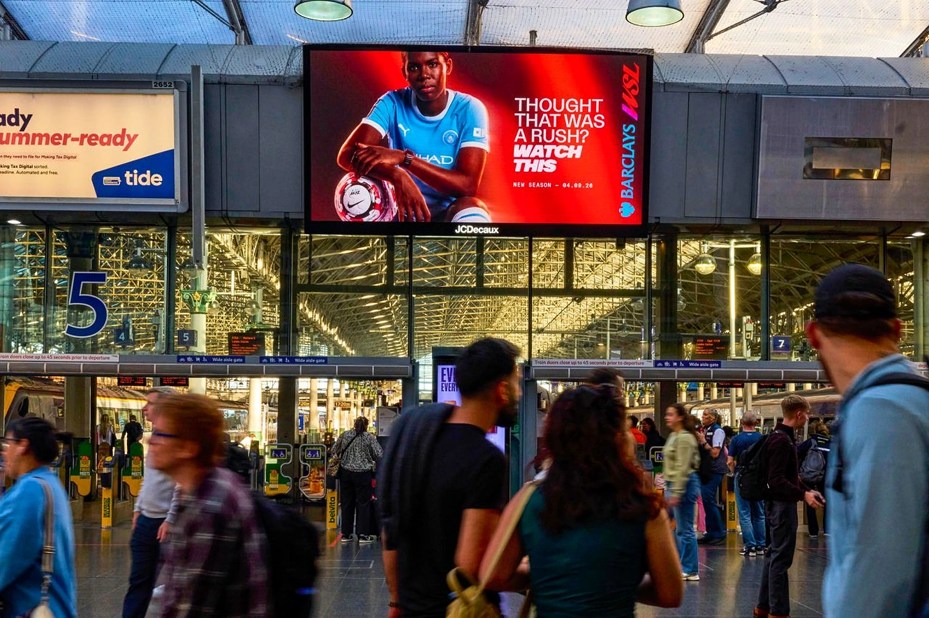 Pantalla digital de Barclays Women’s Super League en una estación del Reino Unido con una futbolista y el mensaje Thought that was a rush? Watch this.