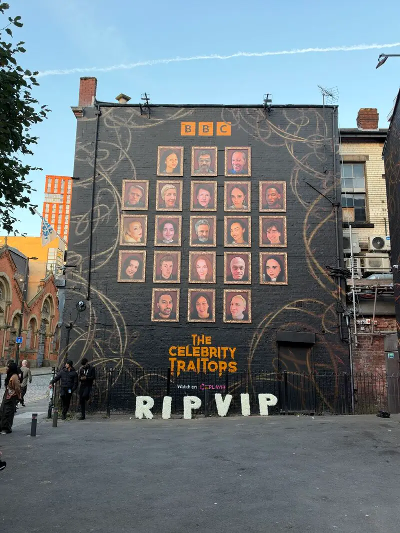 Mural de The Celebrity Traitors en Manchester con Claudia Winkleman al centro y mensajes sobre banishments, recruitments y betrayals.