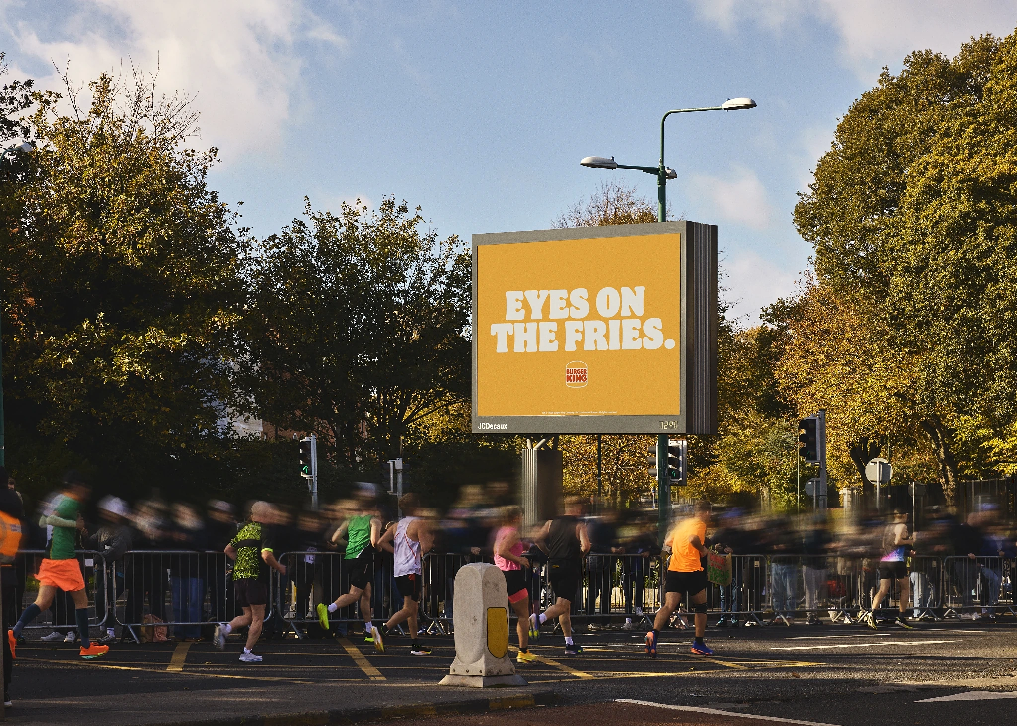 Burger King Dublin Marathon OOH Eyes on the Fries Billboard de Burger King en la ruta del Dublin Marathon con el mensaje Eyes on the fries mientras corredores pasan frente al anuncio.