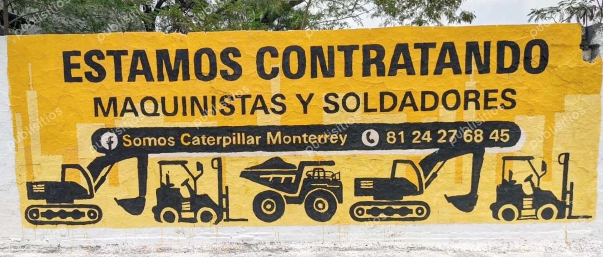 Barda pintada de amarillo con convocatoria de Caterpillar Monterrey para contratar maquinistas y soldadores en Nuevo León.