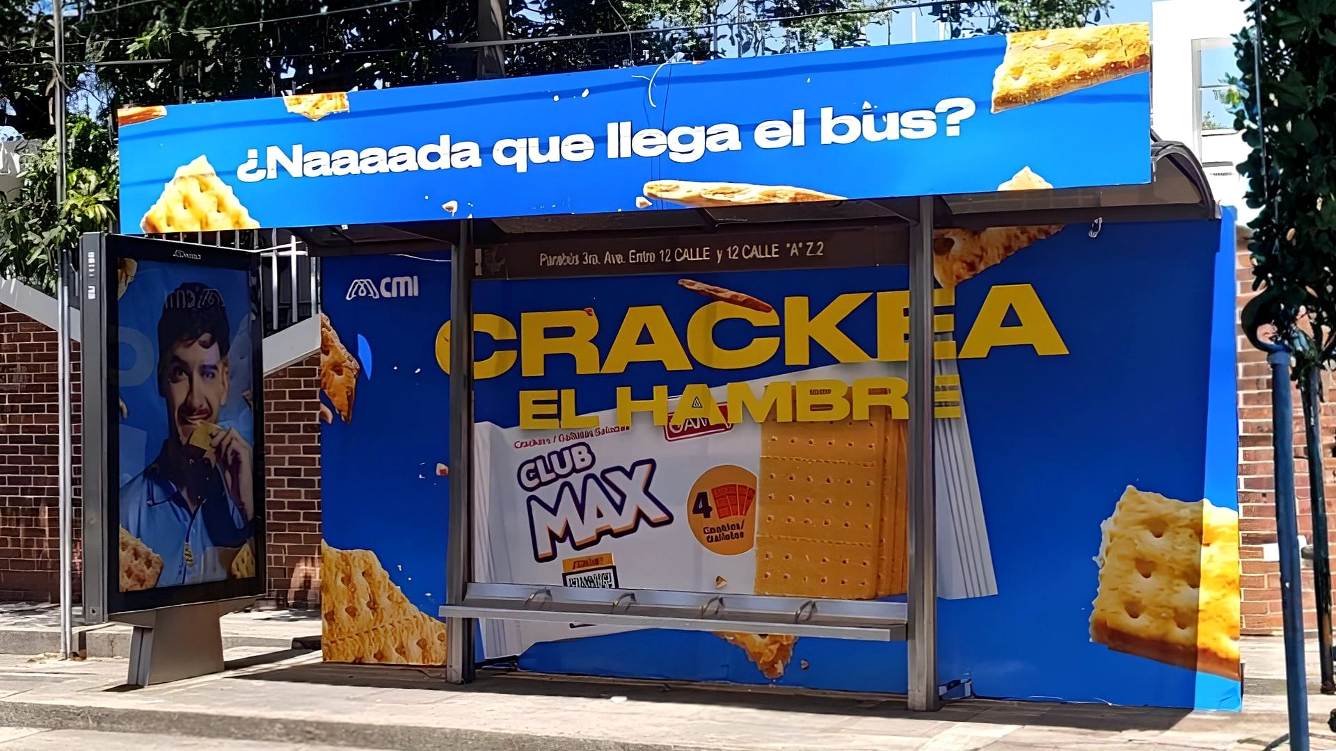 Publicidad exterior de Club Max Crackea el Hambre en Guatemala con fondo azul, paquete Club Max y galletas saladas alrededor del anuncio.