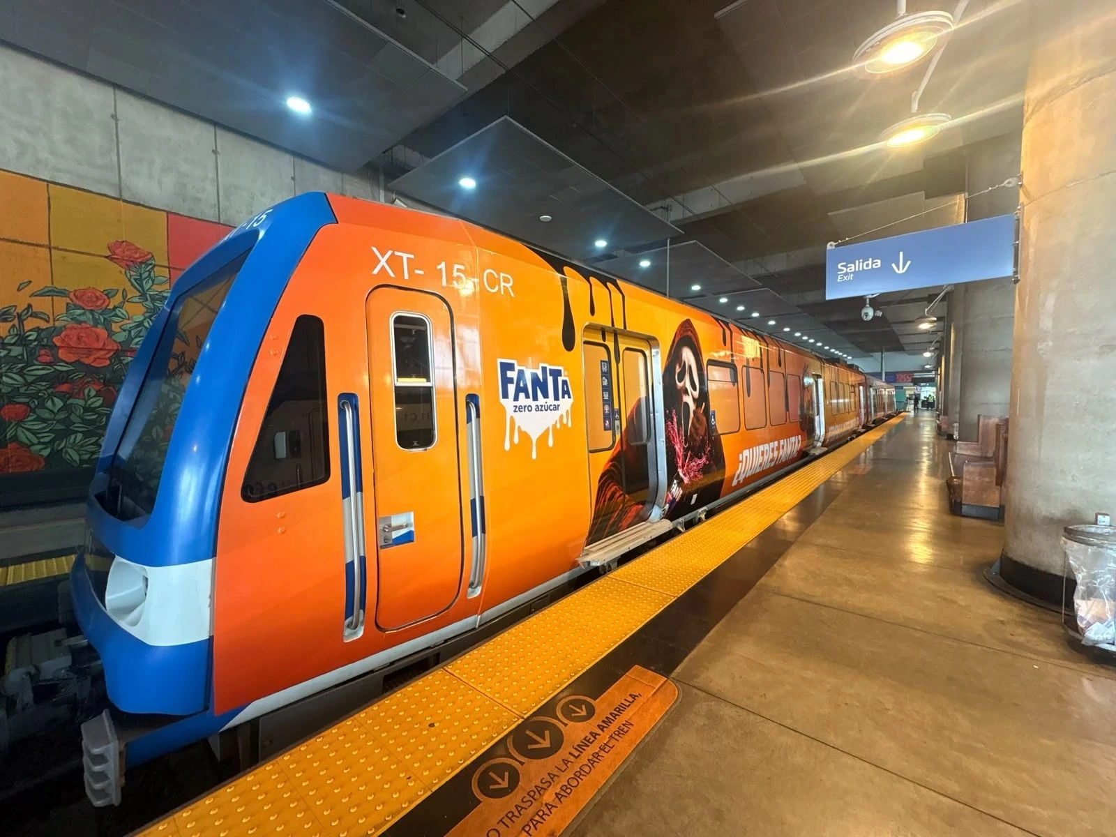 Tren de EFE completamente brandeado por Fanta en color naranja dentro de una estación.