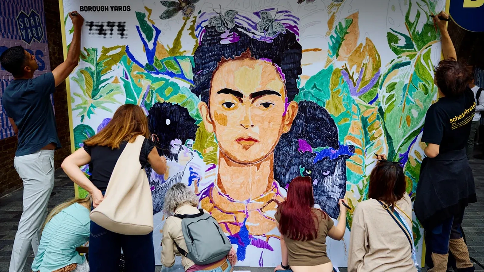 Instalación pública de Frida Kahlo en Londres con un gran retrato colaborativo inspirado en Self-Portrait with Thorn Necklace and Hummingbird.