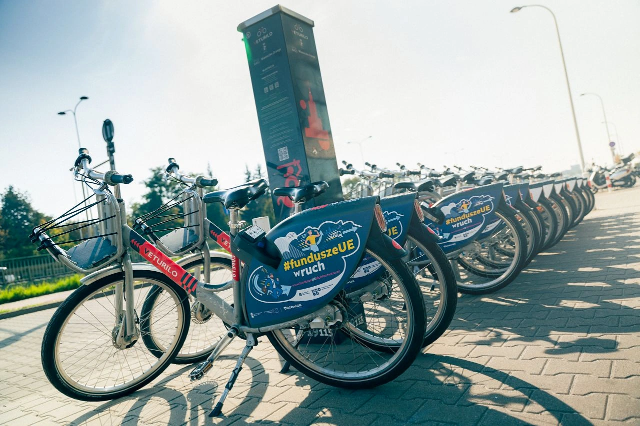 Fila de bicicletas Veturilo en Varsovia con la campaña #funduszeUEwruch de Fundusze Europejskie dla Mazowsza en sus paneles laterales.