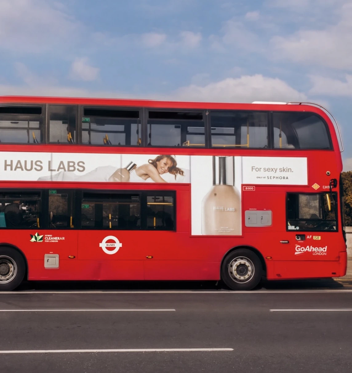 Autobús rojo de dos pisos en Londres con publicidad de Haus Labs For sexy skin, producto y disponibilidad en Sephora.