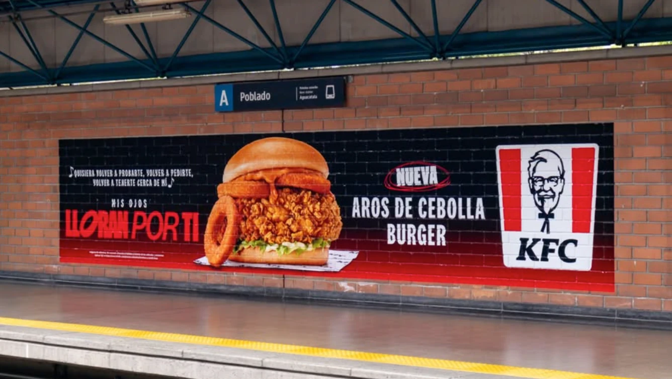 Publicidad de KFC Colombia para la Aros de Cebolla Burger instalada en una plataforma de metro.