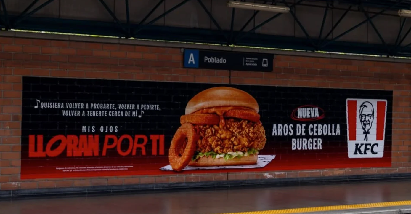 Campaña de KFC Colombia para la Aros de Cebolla Burger en un muro publicitario de la estación Poblado con el mensaje Mis ojos lloran por ti.