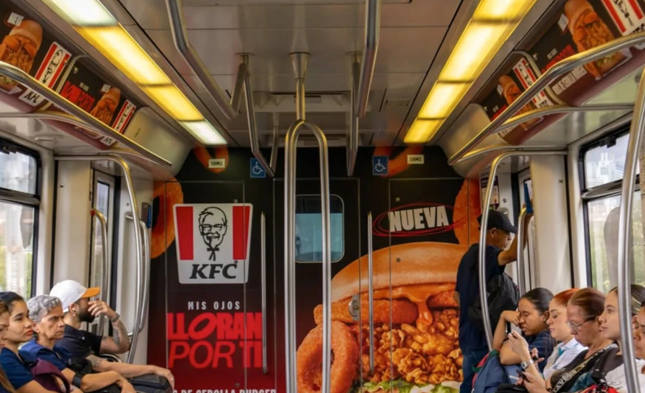 Interior de tren intervenido con publicidad de KFC Colombia para la Aros de Cebolla Burger.