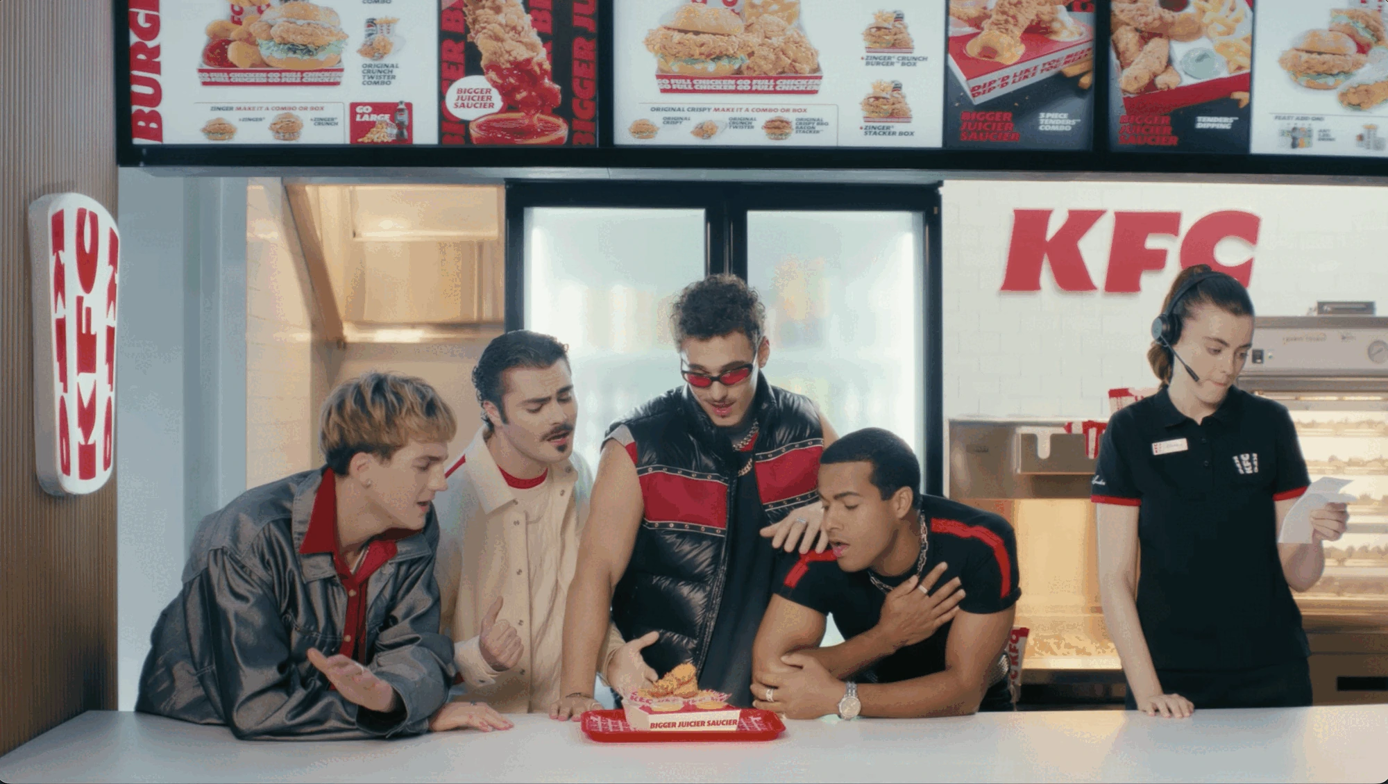 Escena del hero film de KFC Australia con una boyband ficticia reunida alrededor de una bandeja de Chicken Tenders dentro de un restaurante KFC.