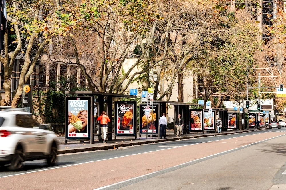 Serie de paradas de autobús en Australia cubiertas con piezas OOH de KFC More Tender Than Ever mostrando Chicken Tenders y mensajes de producto.