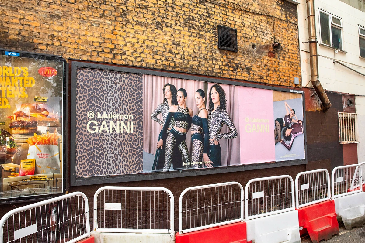 Campaña mural de Lululemon x GANNI en Londres con estampado leopardo, modelos de la colección y piezas gráficas en rosa.