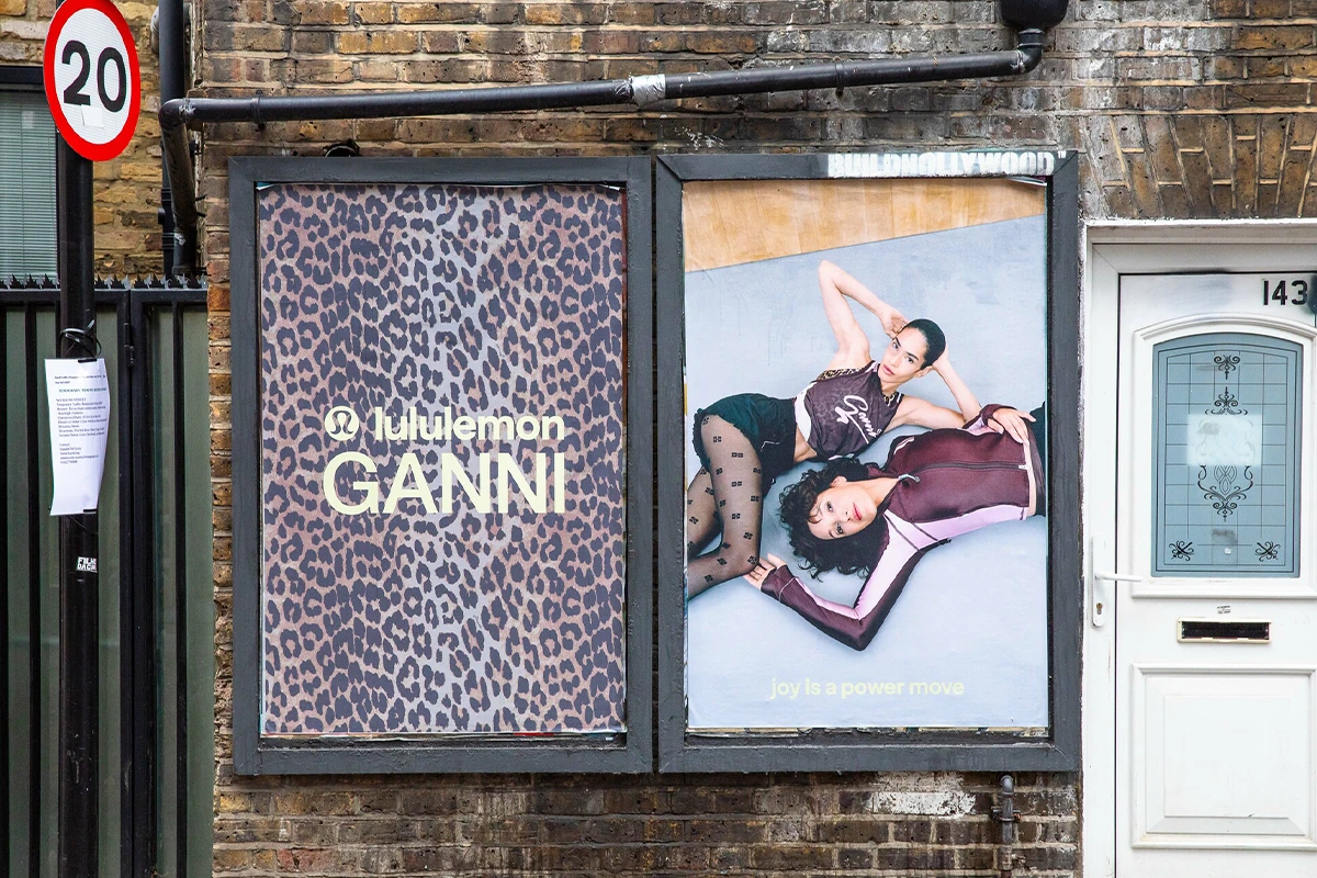 Dos posters de Lululemon x GANNI instalados en una pared de ladrillo en Londres, con estampado leopardo y modelos de la colección.
