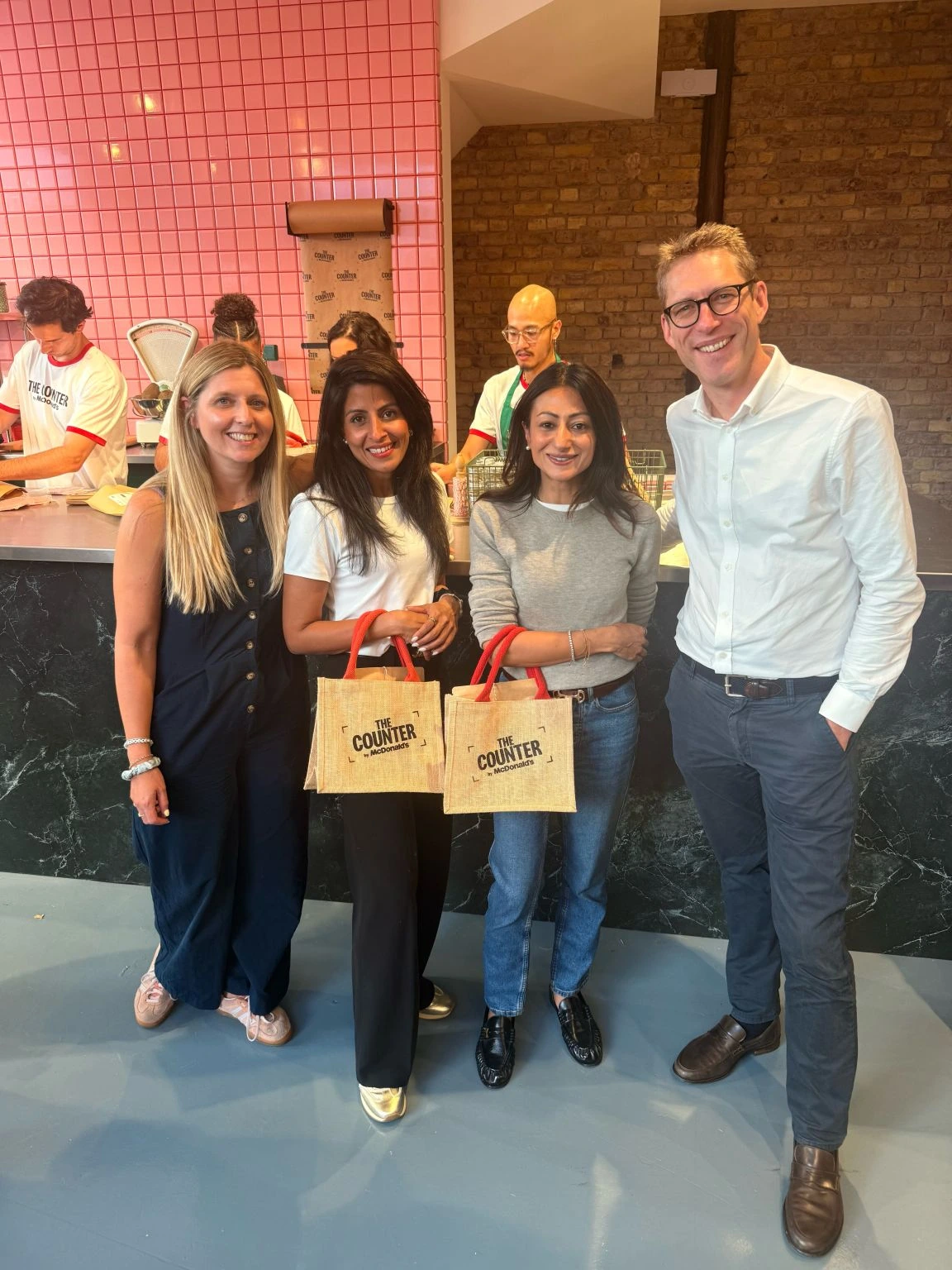 Visitantes posando dentro de The Counter by McDonald’s en un espacio interior con azulejos rosas y bolsas de la activación.