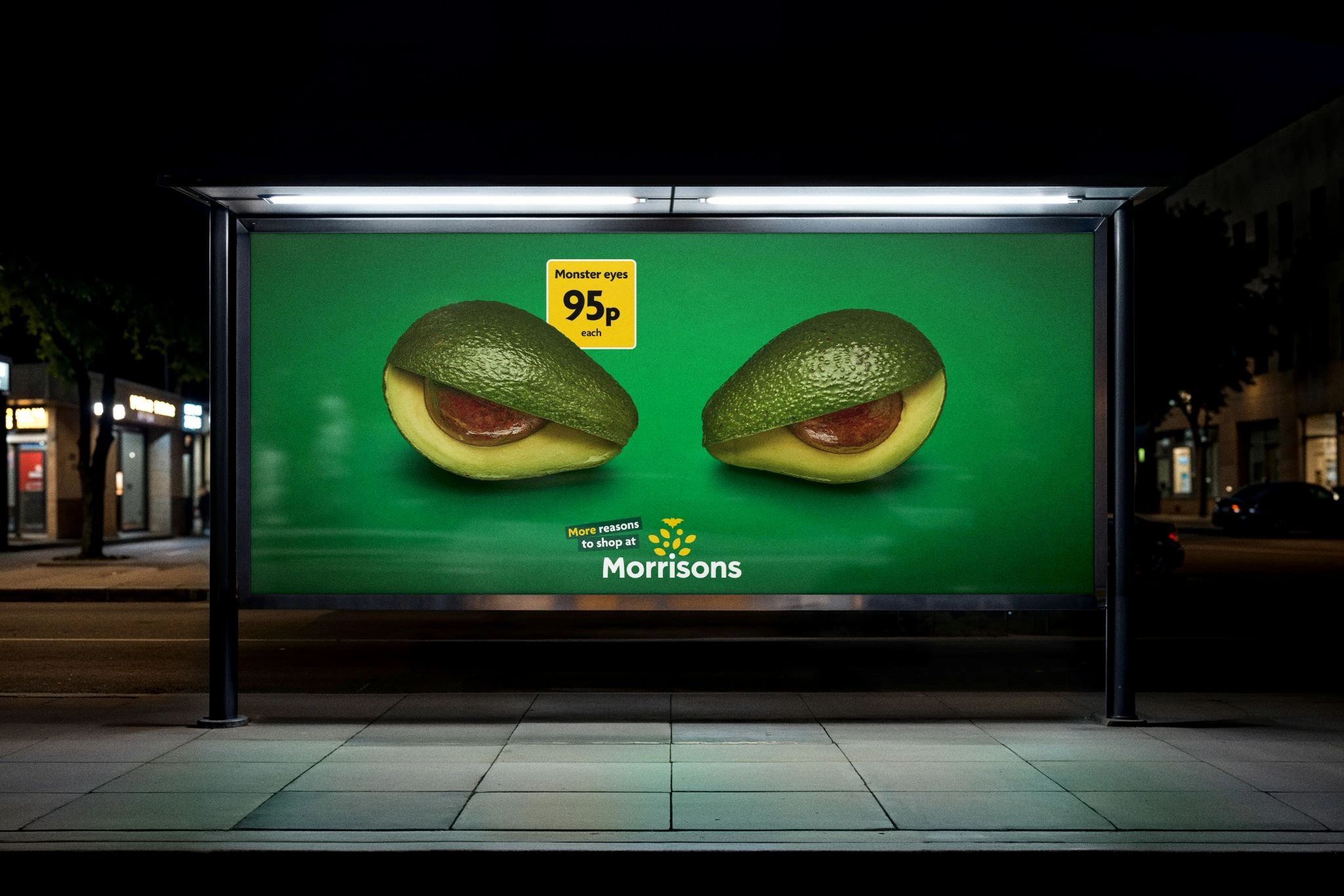 Billboard nocturno de Morrisons con dos aguacates convertidos en ojos de monstruo y el precio 95p.