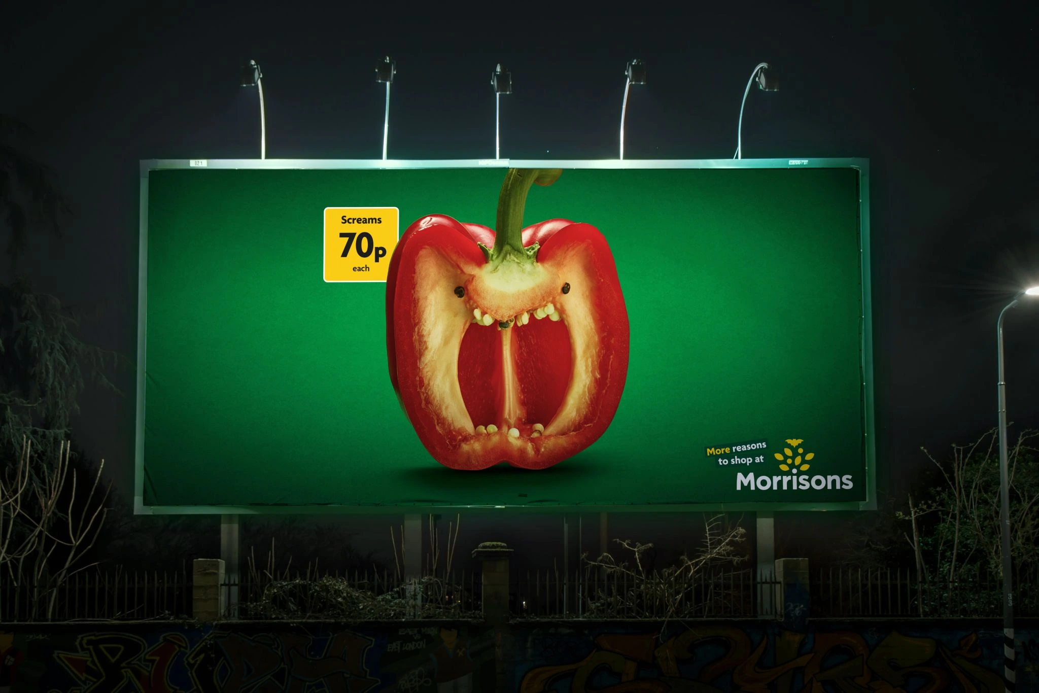 Billboard nocturno de Morrisons con un pimiento rojo transformado en una cara que grita y el precio 70p.