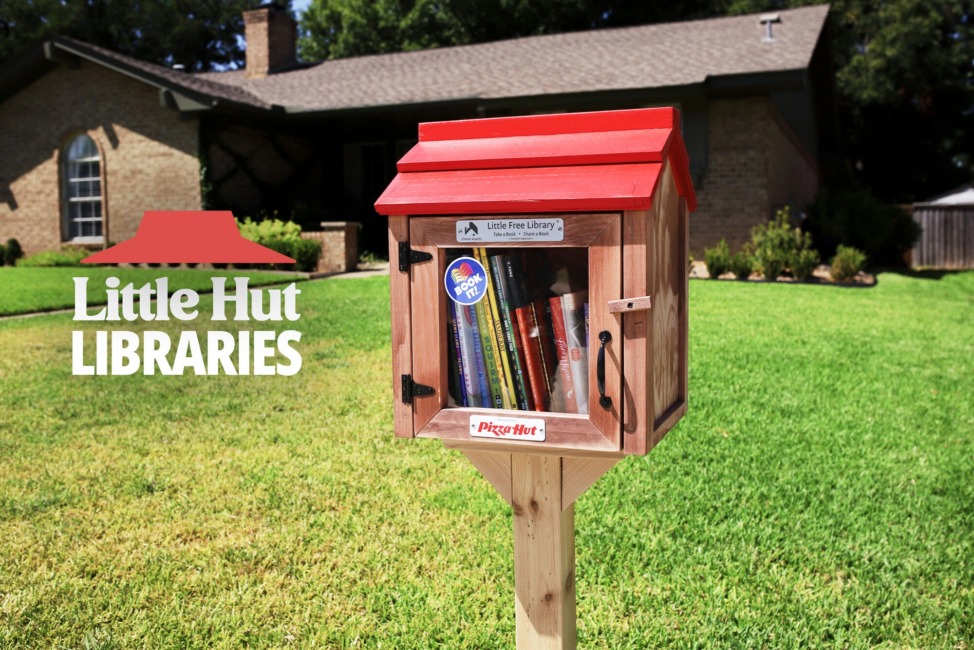 Little Hut Library de Pizza Hut instalada en un jardín residencial, diseñada como una mini biblioteca con techo rojo y libros en su interior.