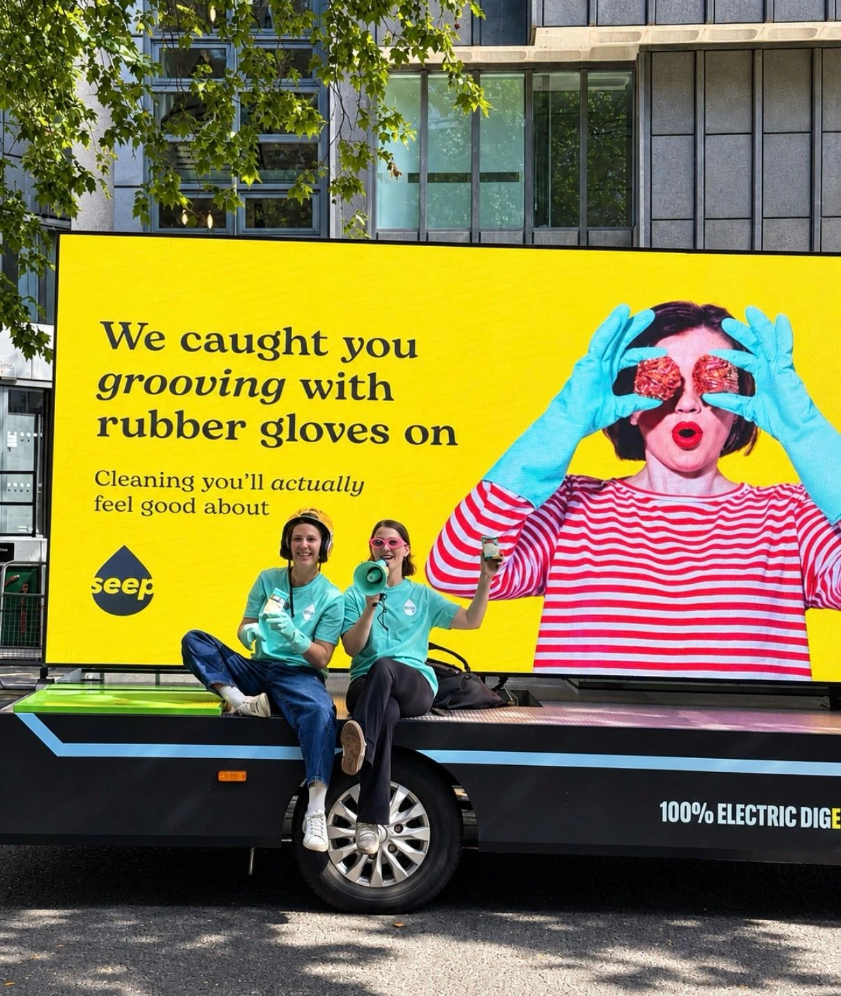 Billboard móvil amarillo de Seep en Londres con dos integrantes del equipo de la marca durante una activación urbana.