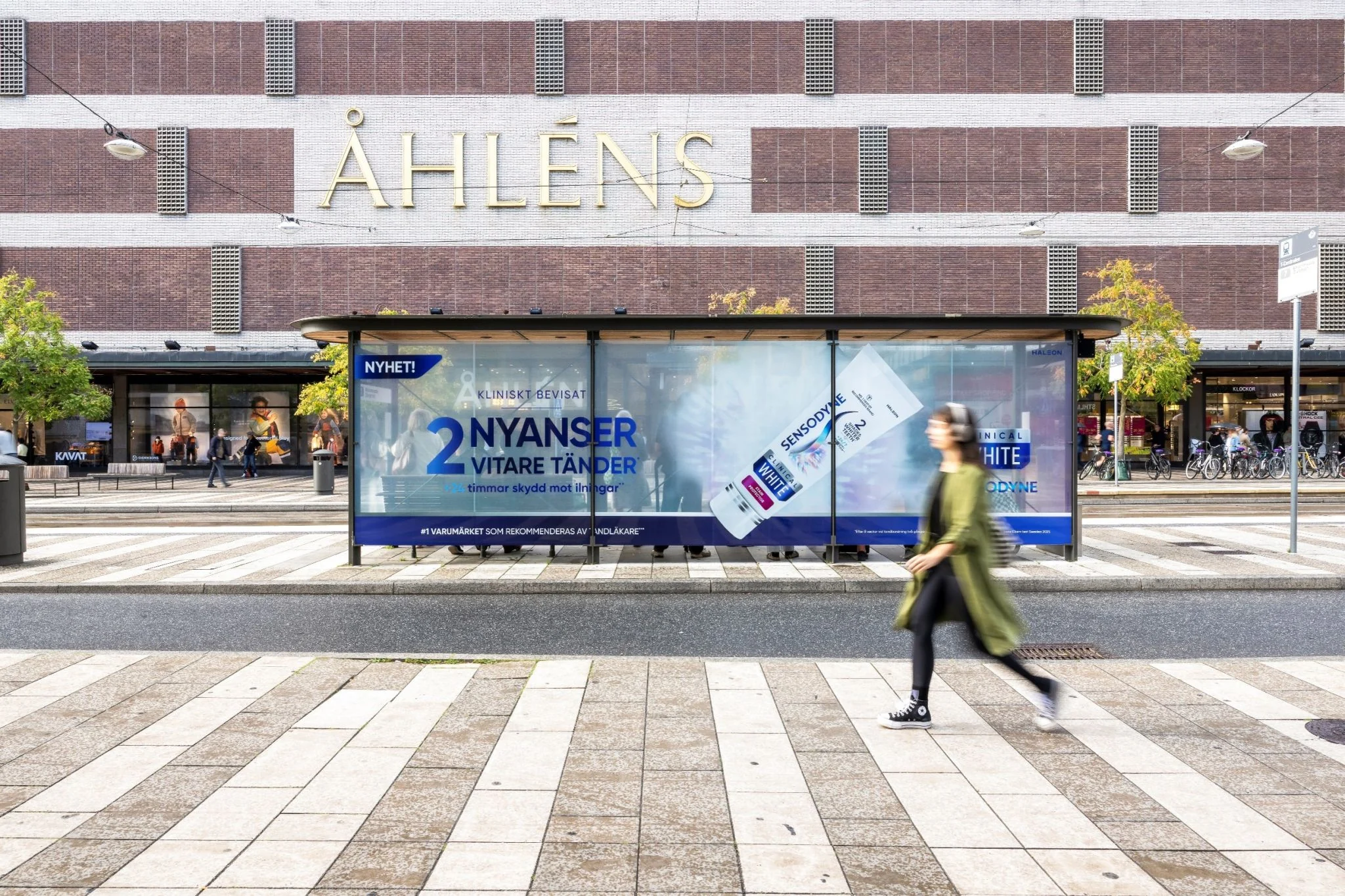 Sensodyne Clinical White bus shelter advertisement in Stockholm showing a large diagonal toothpaste tube and Swedish copy promoting two shades whiter teeth.