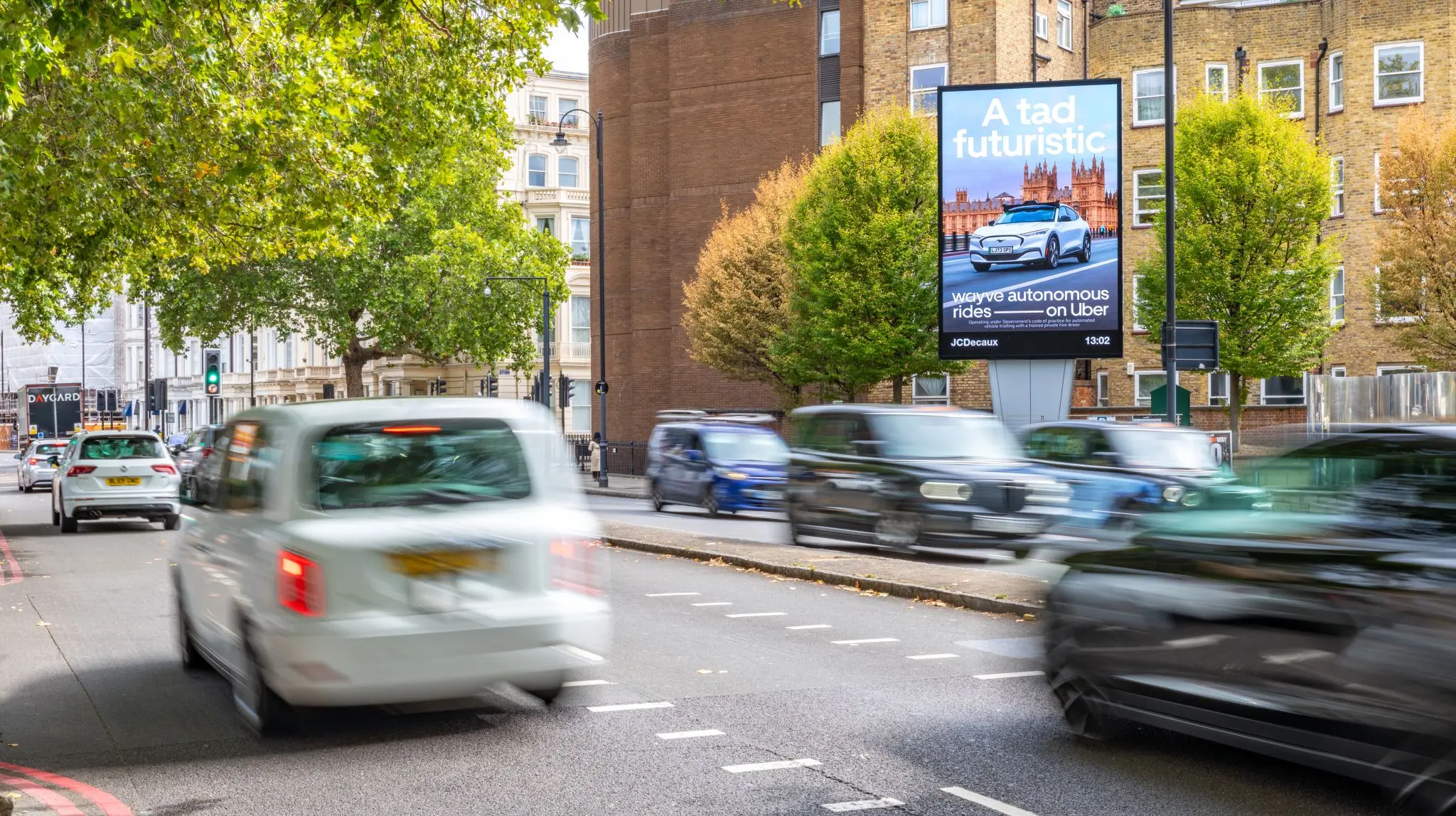 Pantalla digital de Uber y Wayve en Kensington High Street, Londres, promocionando viajes autónomos con el mensaje Right up your street.