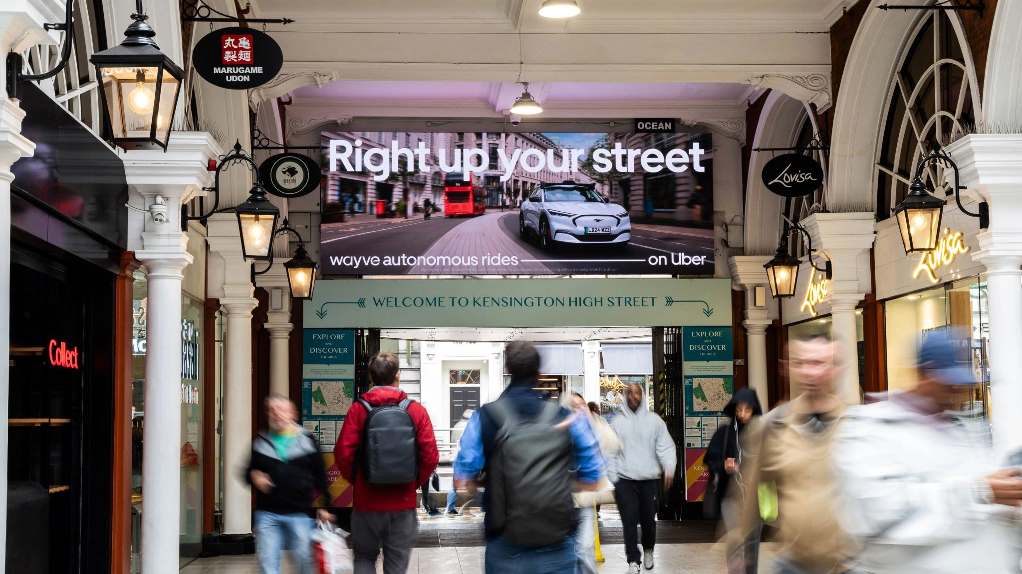 Anuncio digital de Uber y Wayve en Londres con un vehículo autónomo y el mensaje Right up your street.